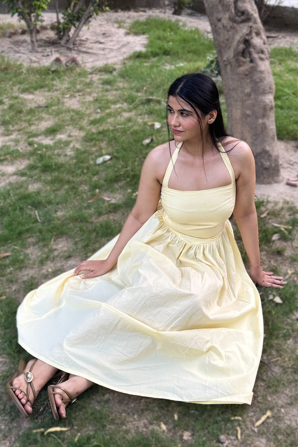 rooshy Butter Babe Corset Dress - model sitting on grass in butter yellow off-shoulder puff sleeve dress